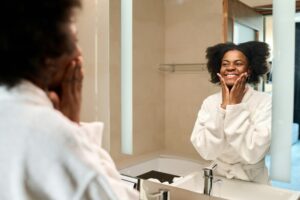 Smiling Black woman looking in mirror