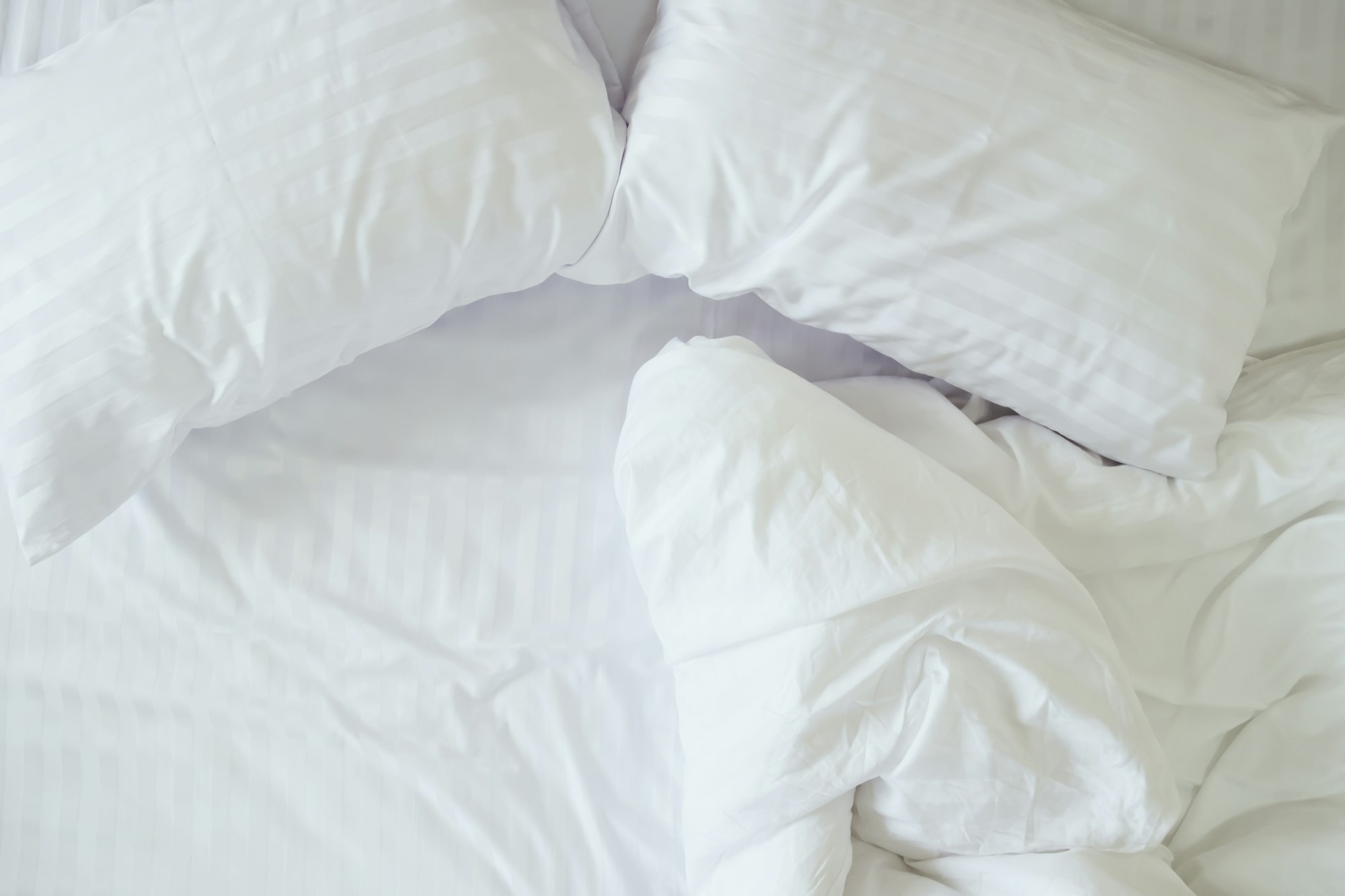 Top view of messy bedding sheets and pillows.